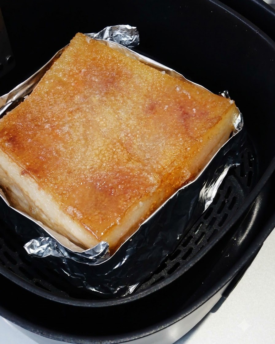 La poitrine de porc rôtie à lintérieur du panier de lair fryer avec sa peau salée dorée.