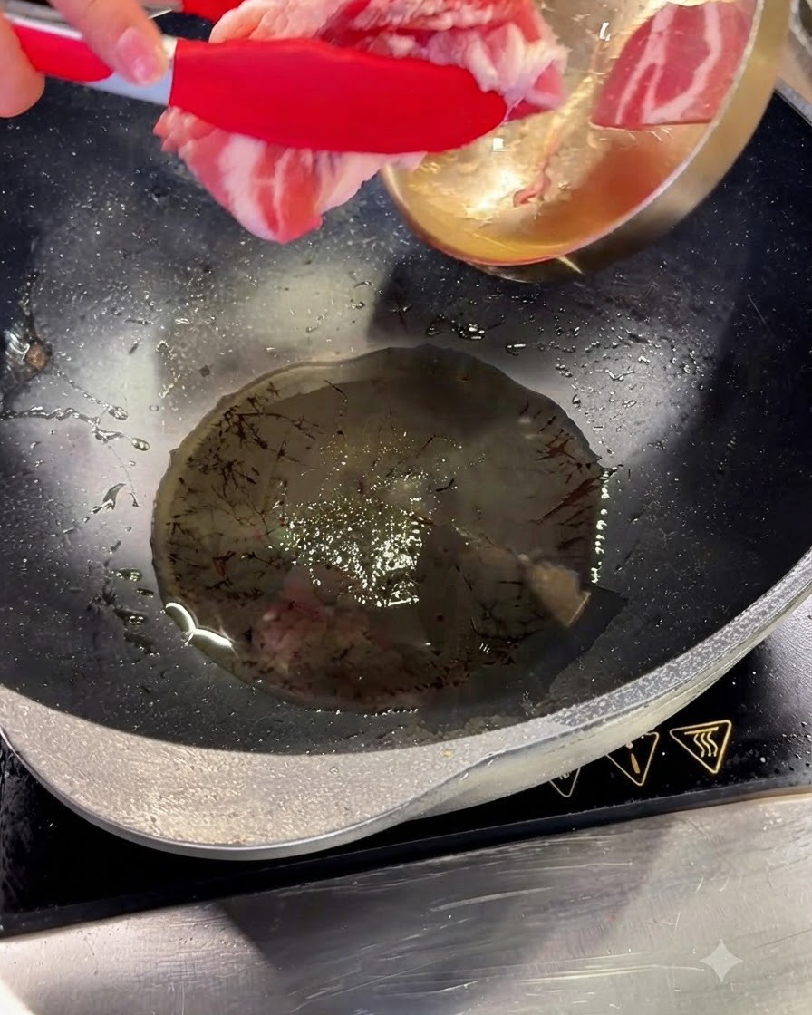 Tranches de poitrine de porc ajoutées à lhuile chaude dans un wok à laide dune pince rouge.
