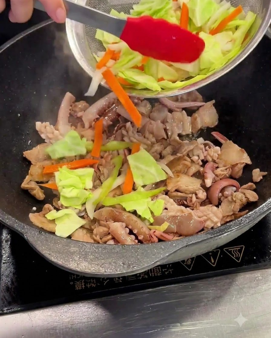 Chou émincé et carottes ajoutés dans le wok depuis une passoire.