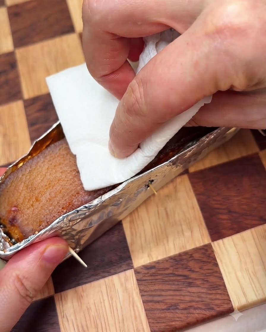 Une feuille dessuie-tout pressée sur la peau du porc dans une barquette en aluminium pour absorber lhumidité, avant dêtre piquée.
