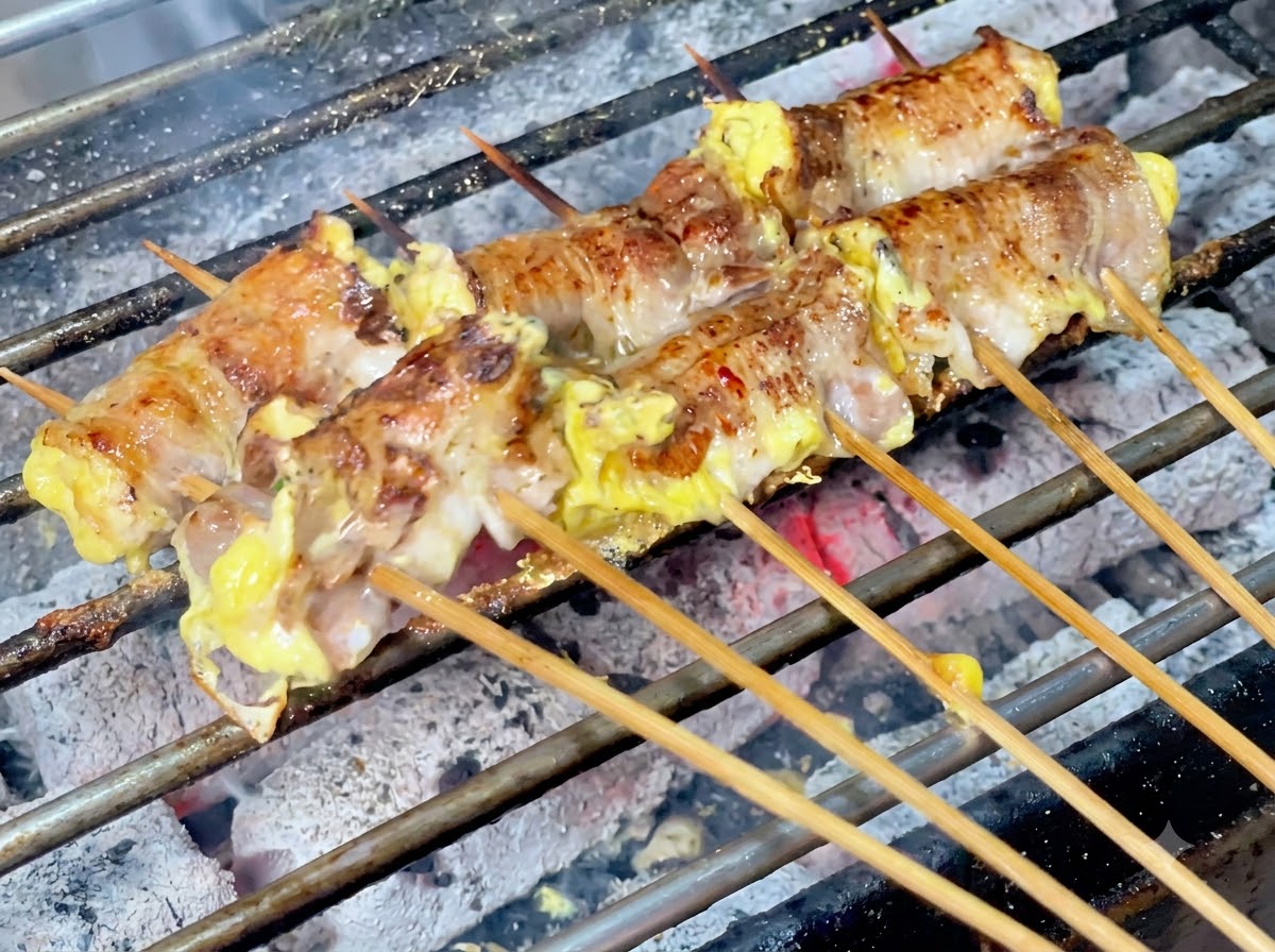 Piment en poudre saupoudré sur les rouleaux de viande grésillants sur le gril à charbon.