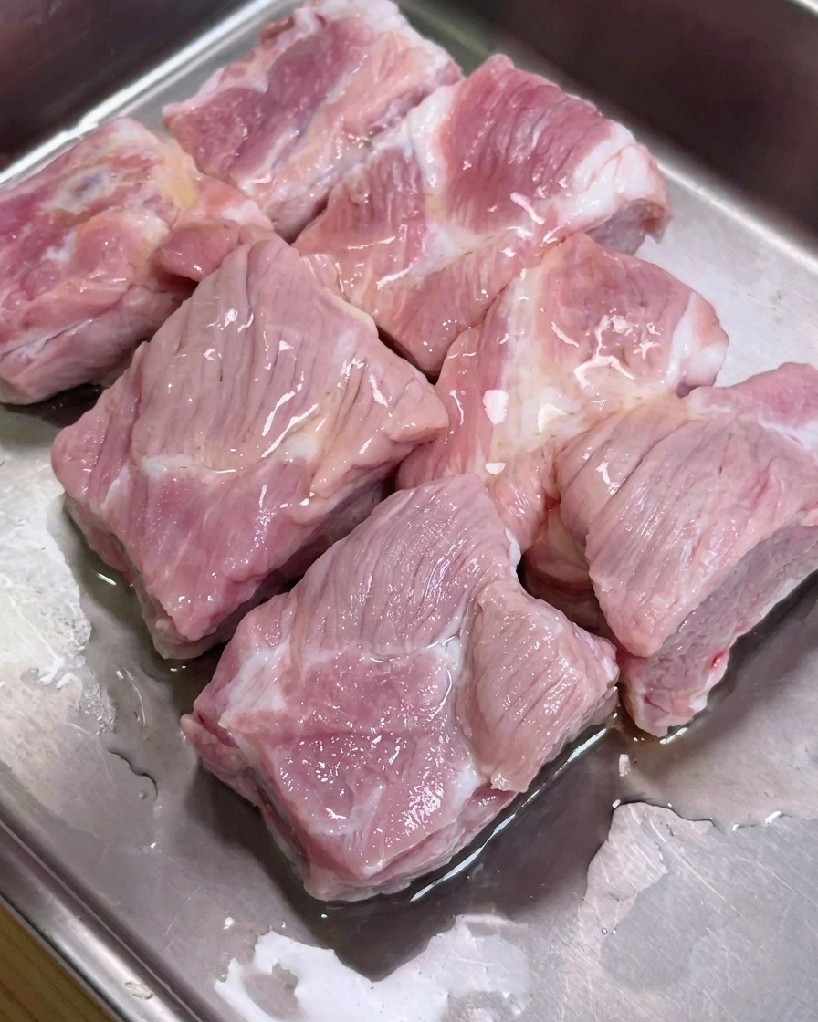 Travers de porc dans un plateau en métal assaisonnés avec les sauces soja, la sauce huître et le poivre.