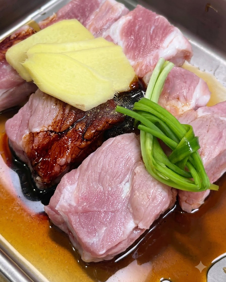 Travers de porc marinés avec des tranches de gingembre, des oignons verts et des sauces dans un plateau.