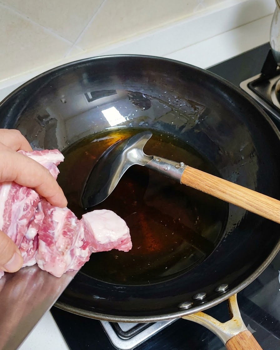 Côtes de porc blanchies ajoutées dans un wok chaud avec de lhuile.