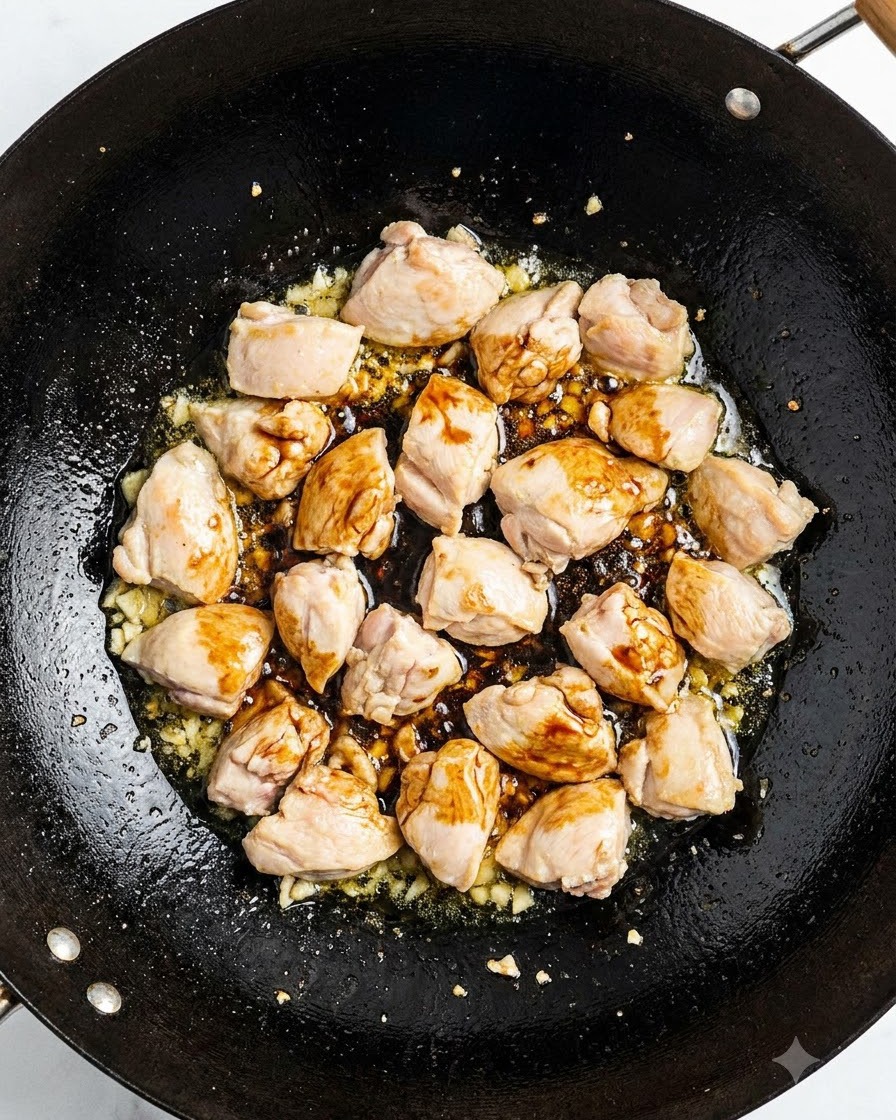 Côtes de porc sautant dans un wok avec de la sauce soja et des aromates.