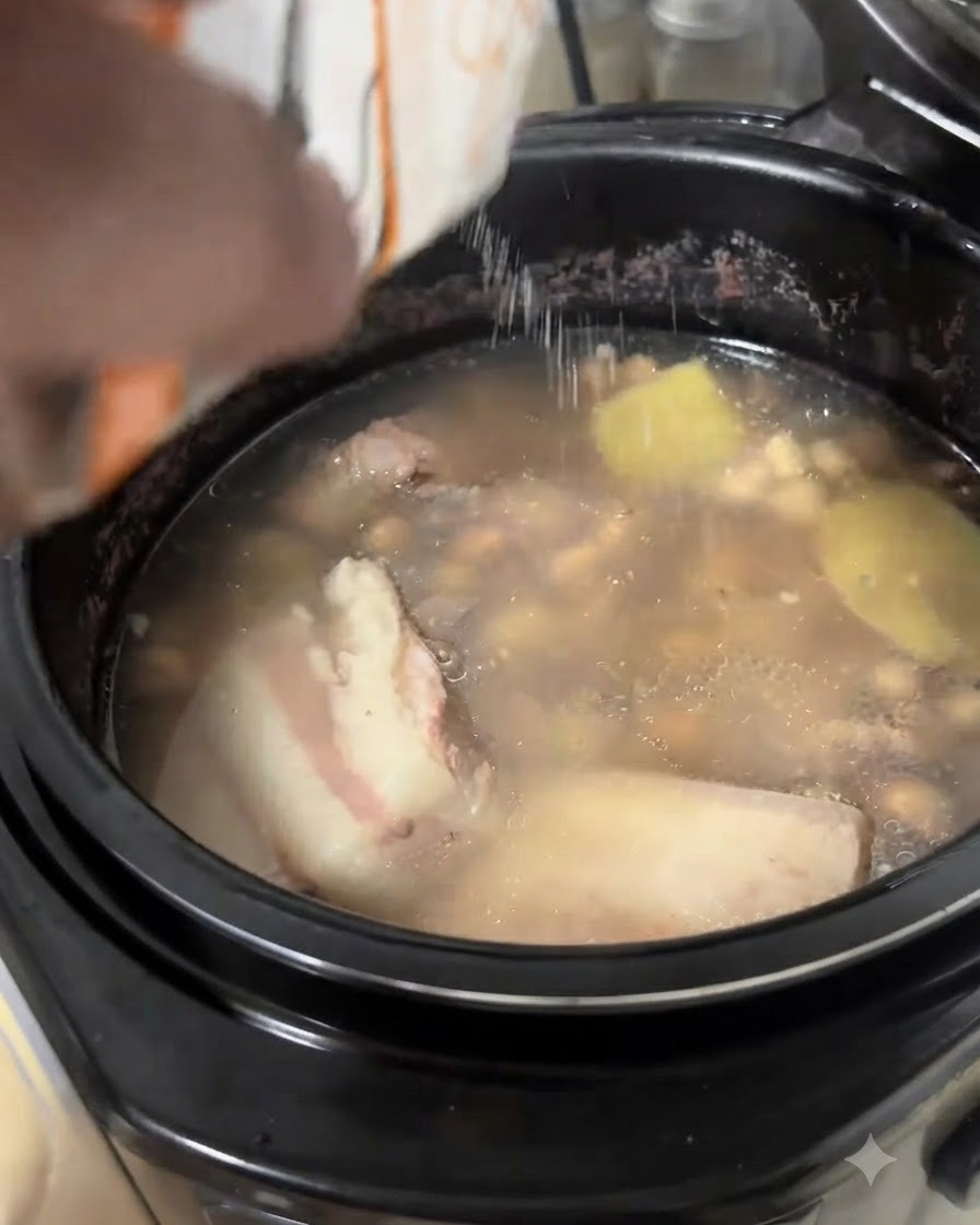 Du sel versé à partir dun sachet blanc dans une soupe de côtes de porc et de cacahuètes frémissante.