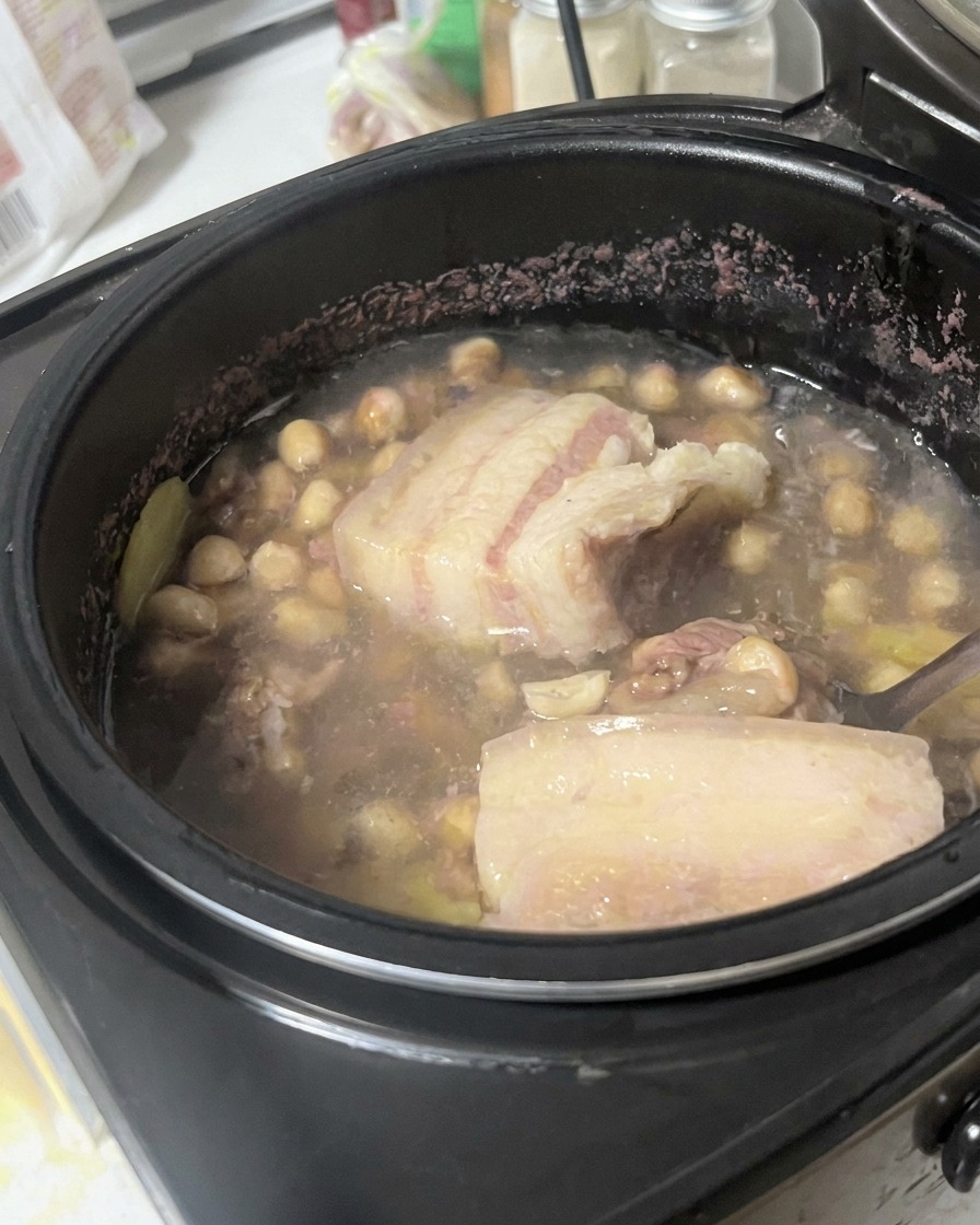 De la poitrine de porc soulevée et examinée avec une cuillère au milieu du mélange de bouillon.