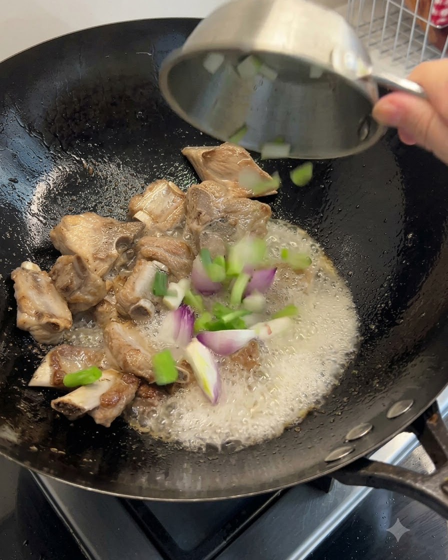 Des oignons verts, du gingembre et des fruits de mer séchés jetés dans le wok avec les côtes.