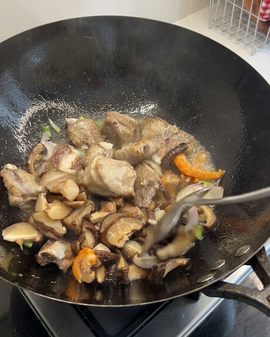 Des carottes coupées en dés et des grains de maïs mélangés au contenu grésillant du wok.