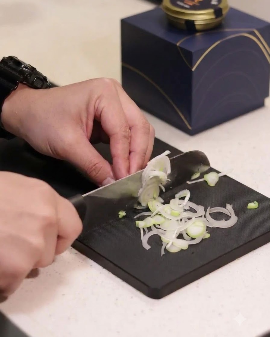 Oignons verts coupés en fines rondelles sur une planche à découper noire.