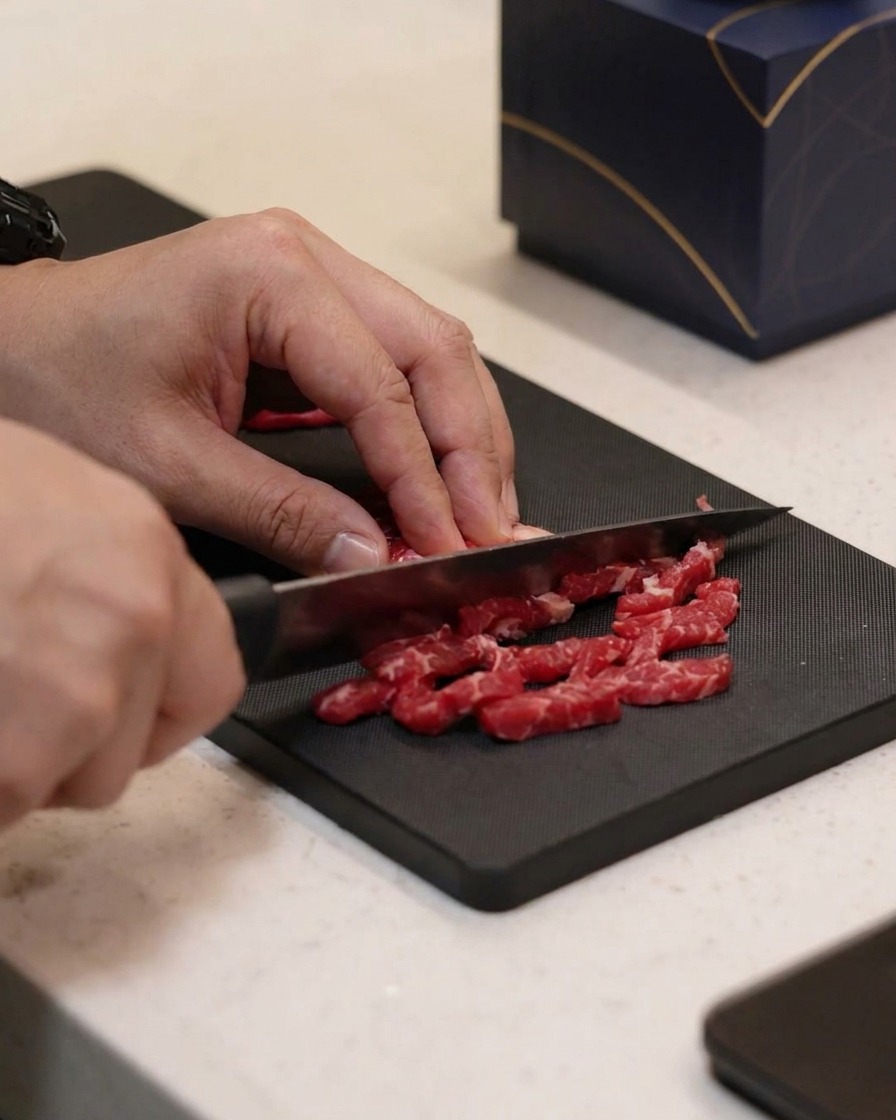 Petites lamelles de bœuf assaisonnées dhuile, de sel et de poivre sur une planche à découper.
