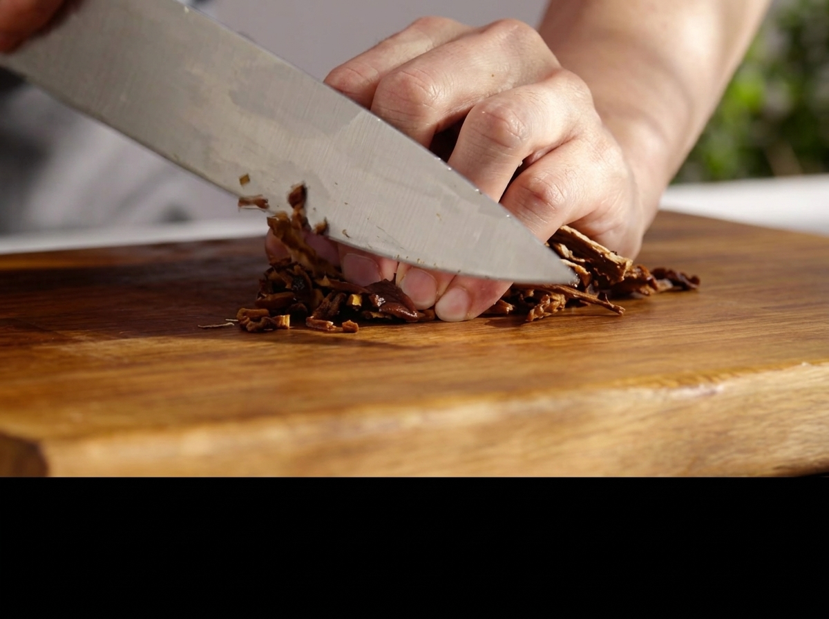Couteau hachant finement des champignons réhydratés sur une planche en bois.