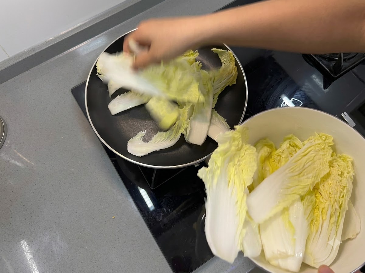 Feuilles de chou chinois placées pour former une couche de fond à lintérieur dune poêle à frire.