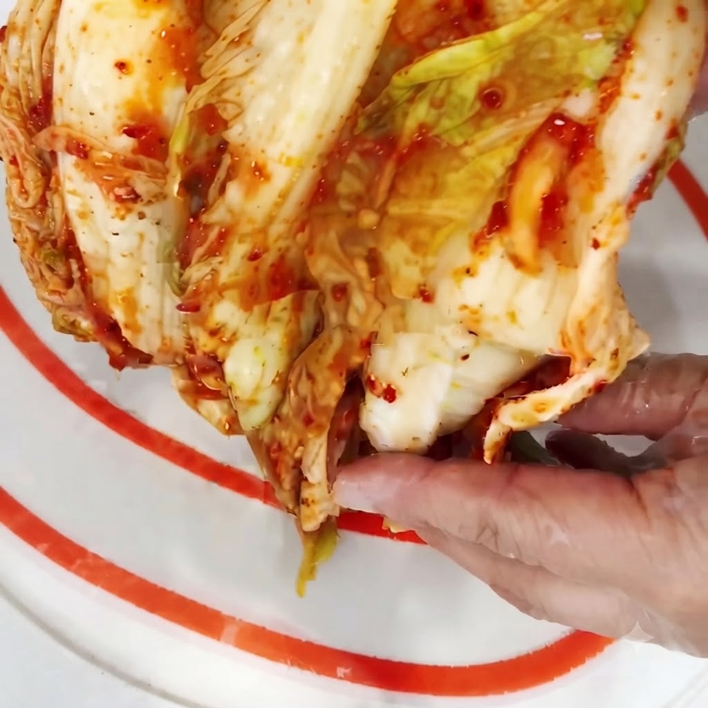 Moitié dune tête de kimchi coupée en petits morceaux sur une planchette à découper.