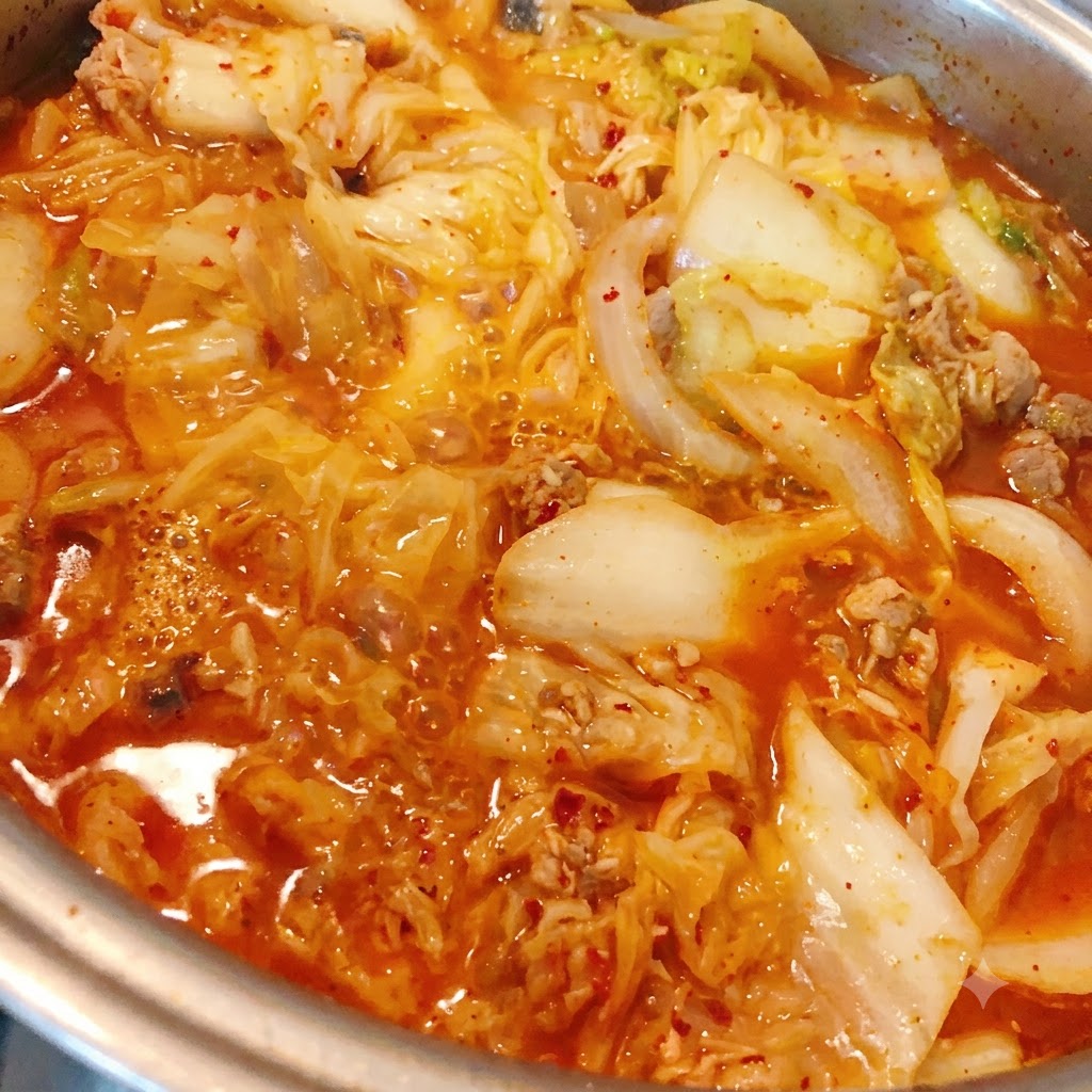 Poudre de piment ajoutée dans le ragoût de kimchi et de thon en train de mijoter.
