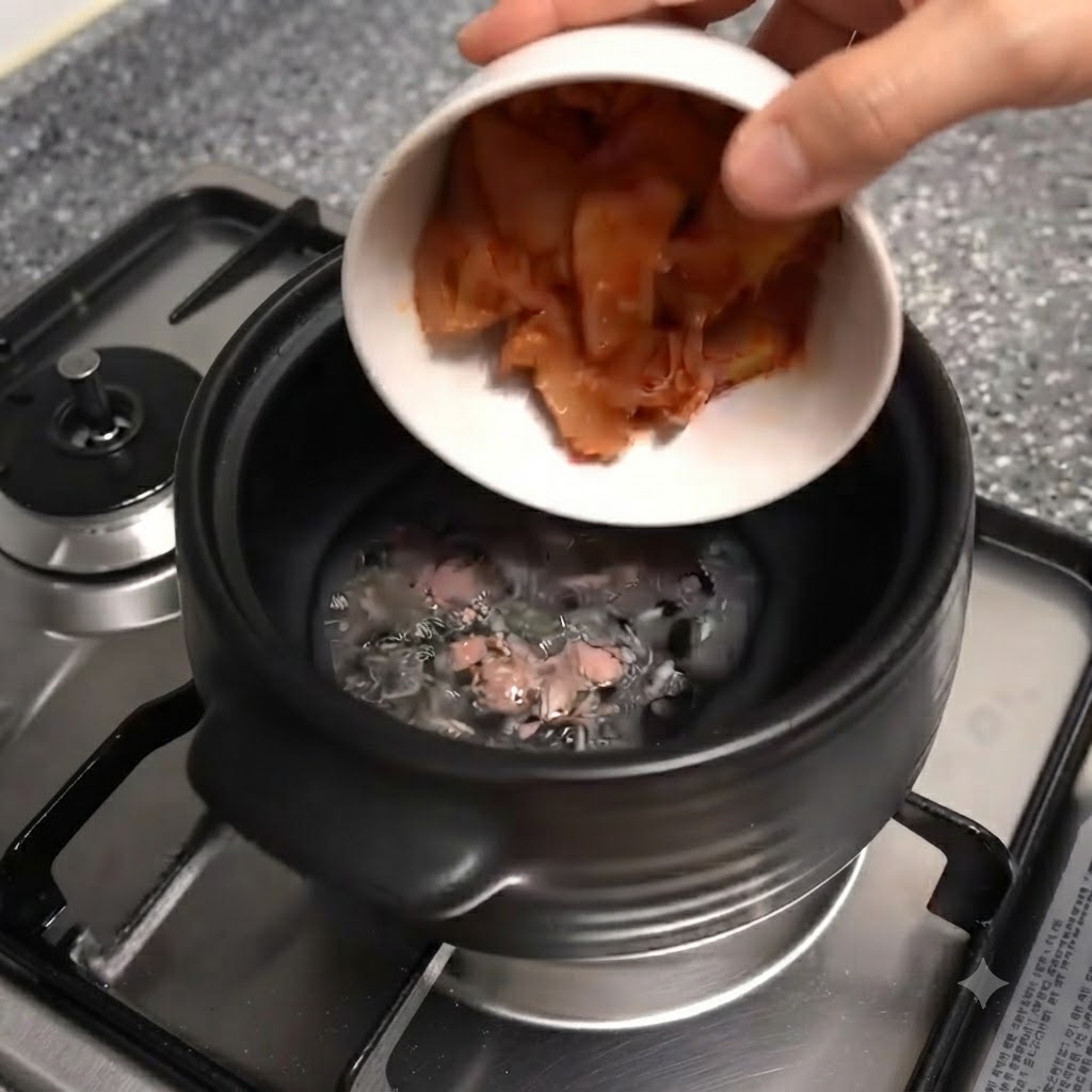Un bol blanc sinclinant pour verser des morceaux de kimchi rouge haché dans le caquelon en terre cuite noir.