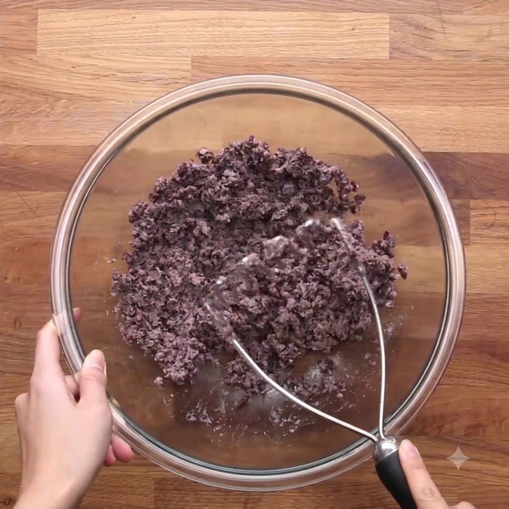 Le mélange doignons et de carottes cuits combiné avec les haricots noirs écrasés dans un bol en verre.