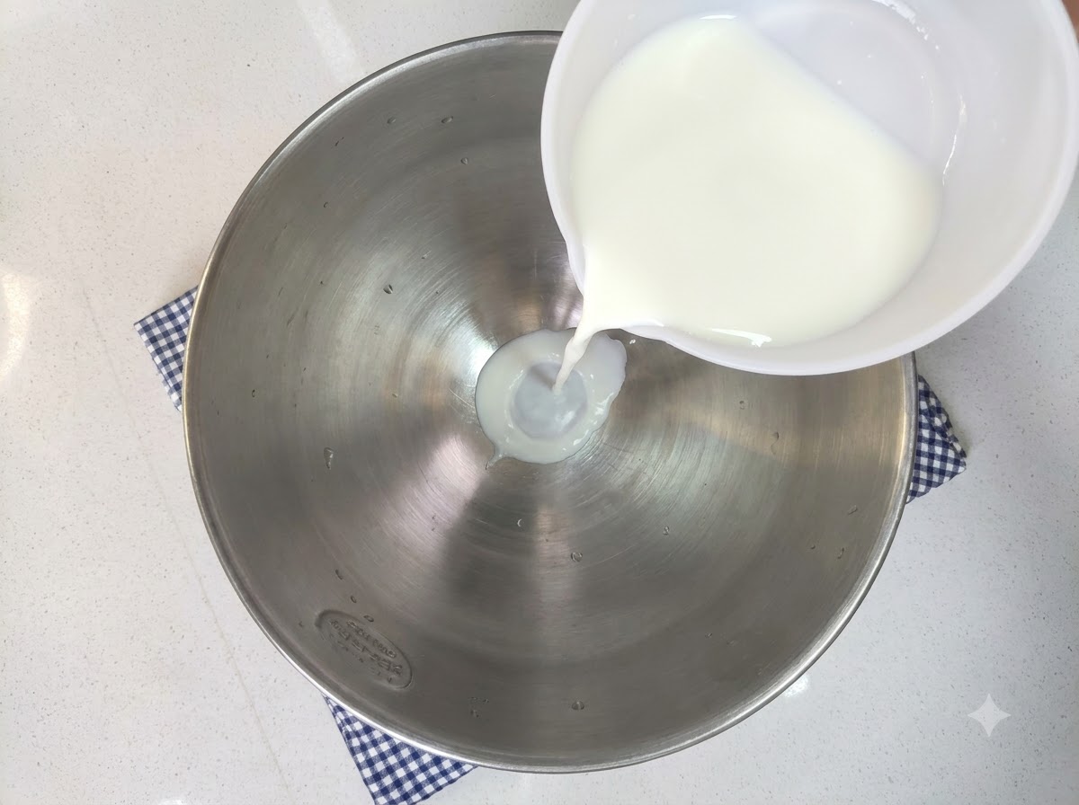 Du lait, du sucre blanc, de la levure, un œuf et de la farine riche en gluten versés dans un grand bol à mélange.