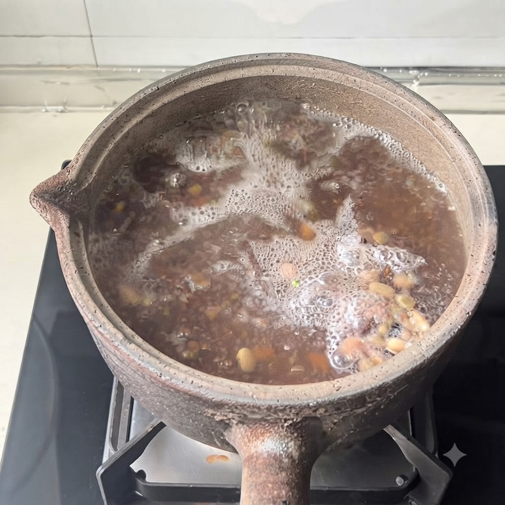 Une casserole en terre cuite avec son couvercle posée sur un brûleur de cuisinière moderne pendant le processus de cuisson.
