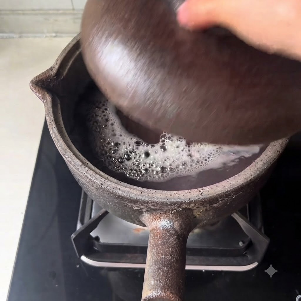 Une vue rapprochée du bouillon foncé frémissant et des haricots bouillonnants à lintérieur de la casserole en terre cuite.