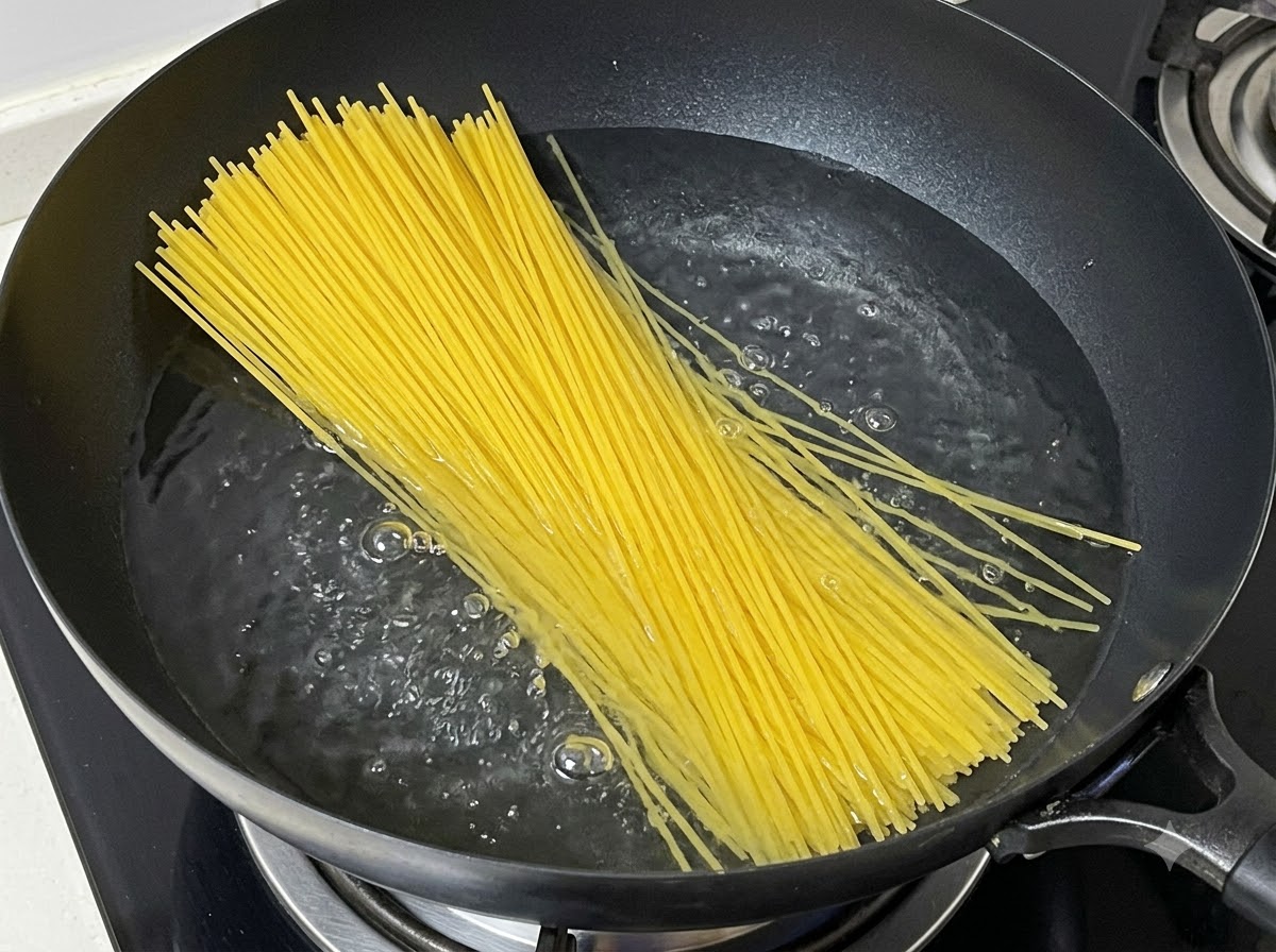 Un paquet de spaghettis secs plongés dans une casserole deau bouillante.