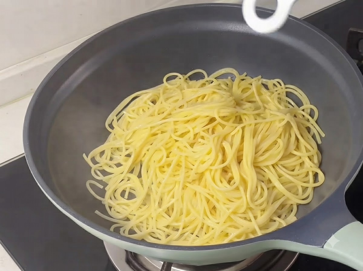 Des brins de spaghettis jaunes cuits amassés à lintérieur dune poêle.
