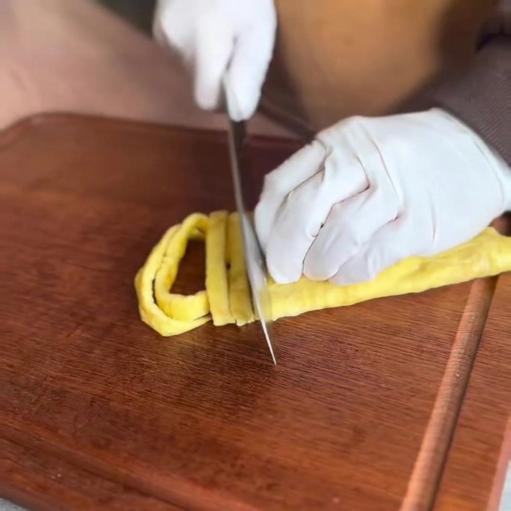 La crêpe dœuf cuite coupée en fines lanières sur une planche à découper en bois.
