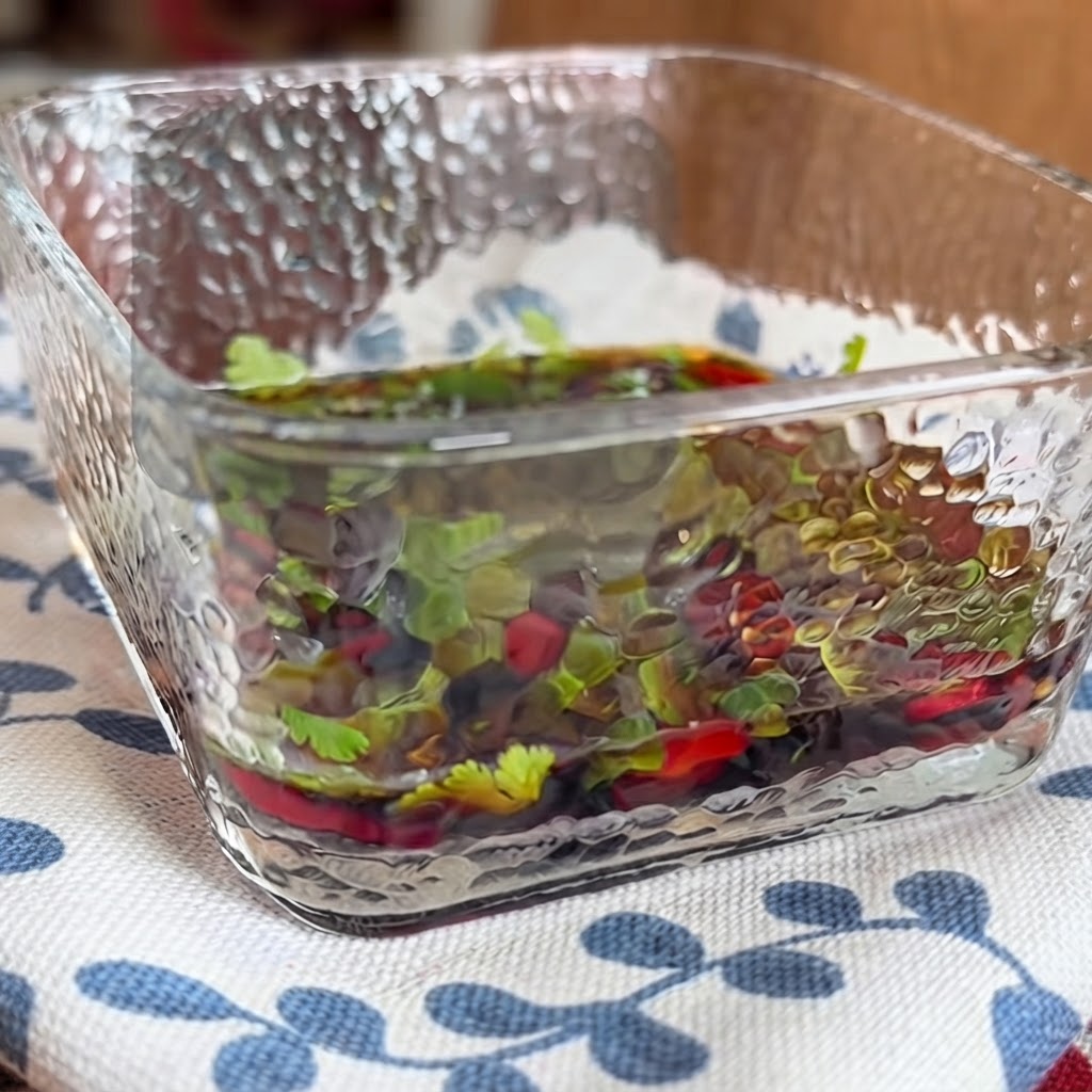 Gros plan sur un plat en verre carré rempli dune sauce trempette savoureuse contenant des herbes et des piments mélangés avec des baguettes.