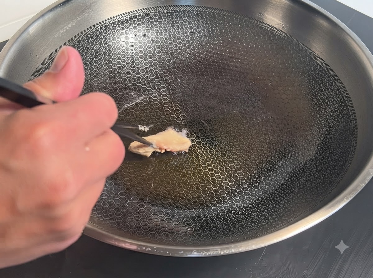 Un seul morceau de poulet enrobé de pâte placé avec des baguettes dans un wok en métal chaud avec de lhuile.
