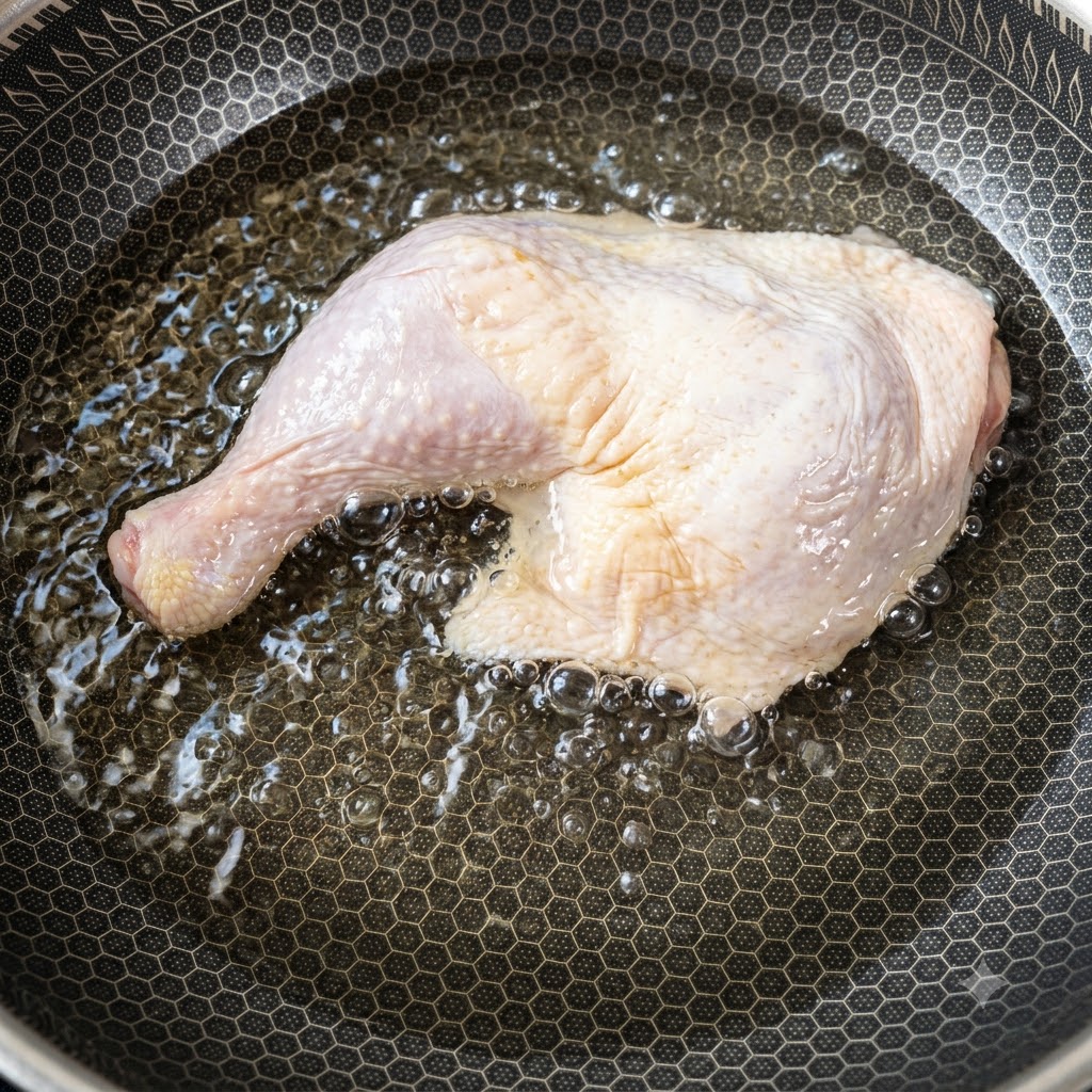 Une grande cuisse de poulet crue placée dans une casserole remplie deau froide qui commence à chauffer.