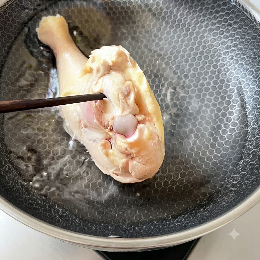 Une cuisse de poulet blanchie replacée dans de leau froide à lintérieur dune casserole.