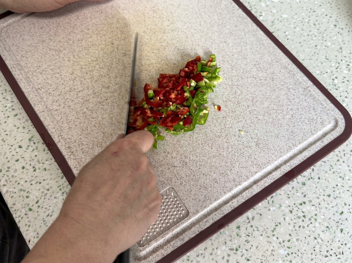 Des piments rouges et verts finement tranchés et émincés sur une planche à découper propre.