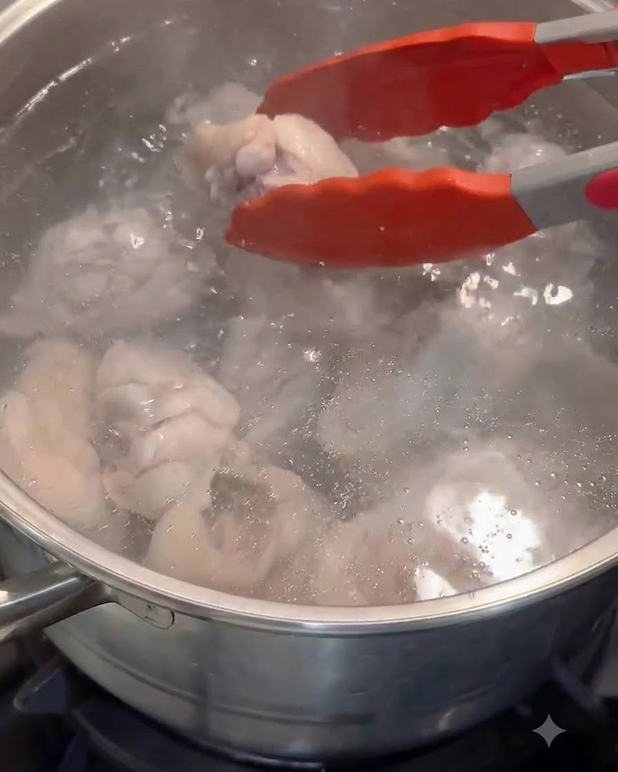 Pinces rouges transférant des morceaux de poulet blanchis dans une casserole deau chaude propre.