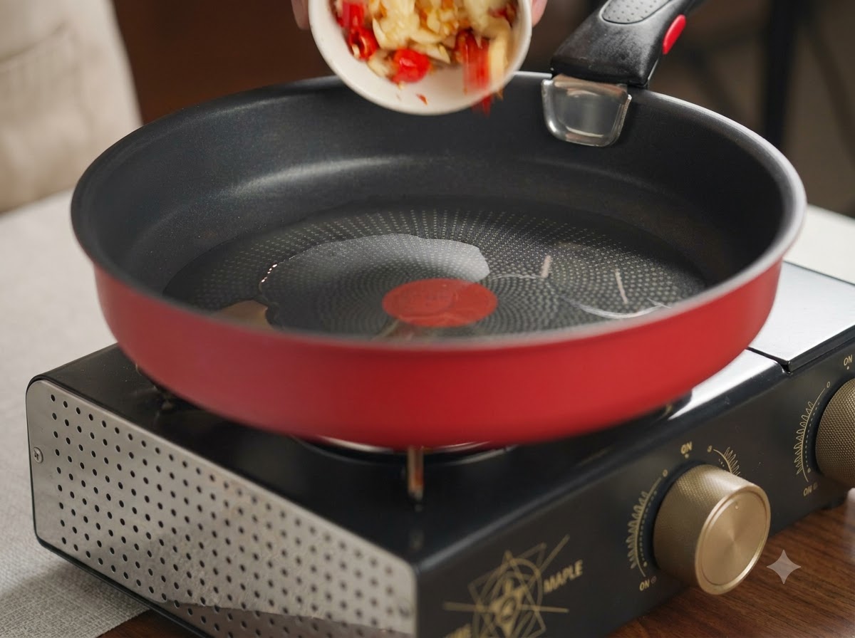 Ail et piments rouges écrasés versés dun petit plat blanc dans une poêle rouge chaude avec de lhuile.