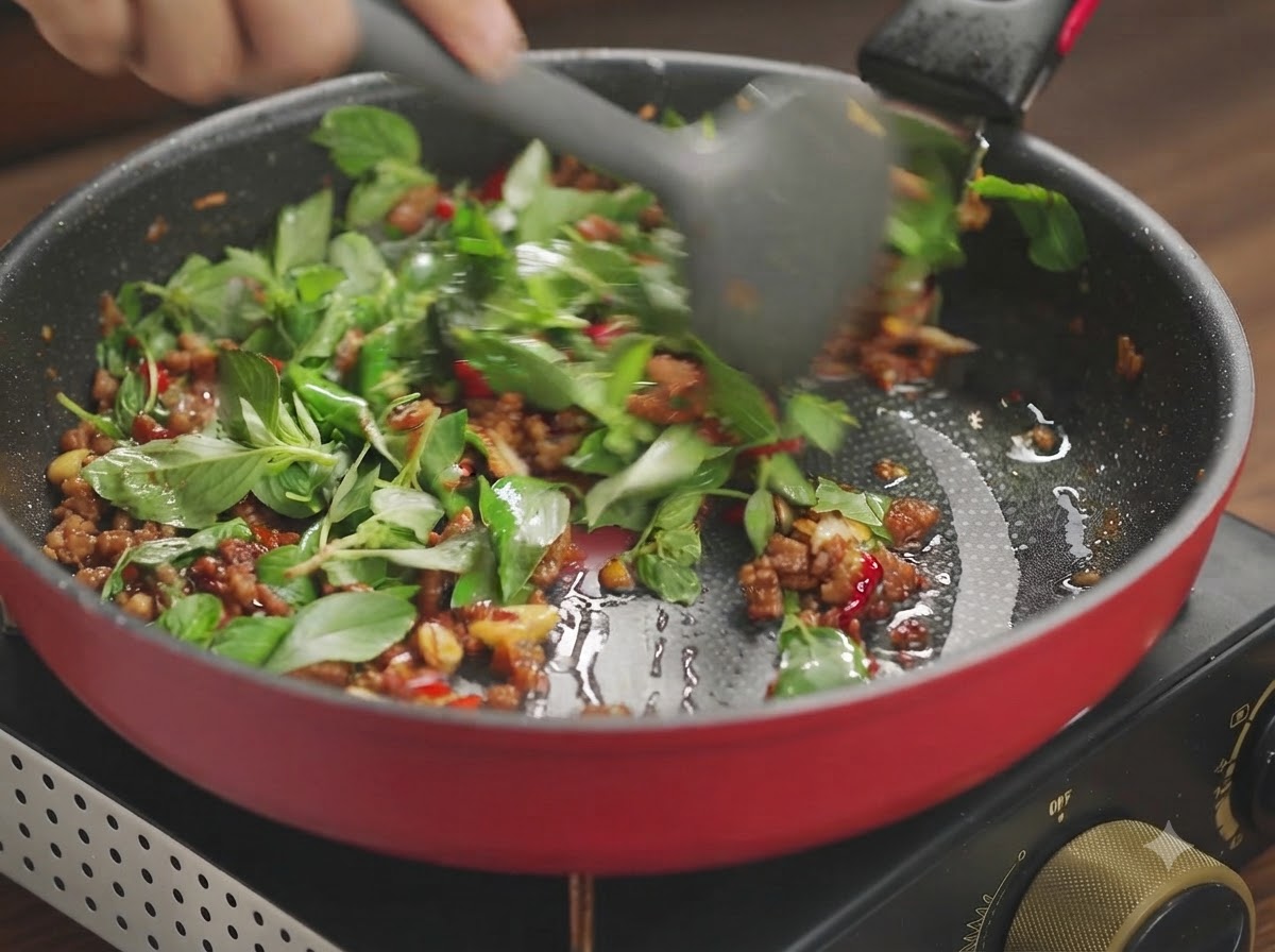 Feuilles de basilic et porc haché sautés ensemble jusquà ce que les légumes verts soient flétris.
