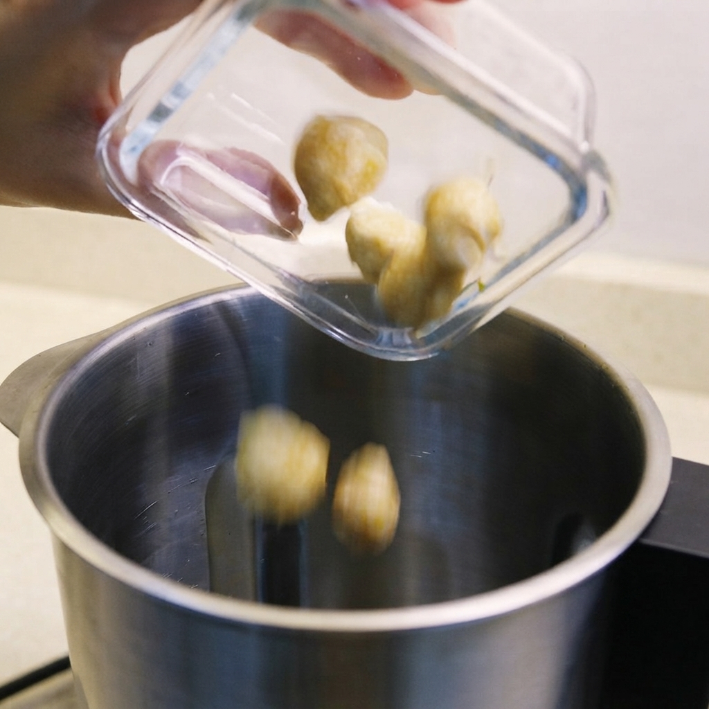 Noix de chandelle, échalotes et belacan sauté versés dans le bol dun mixeur.