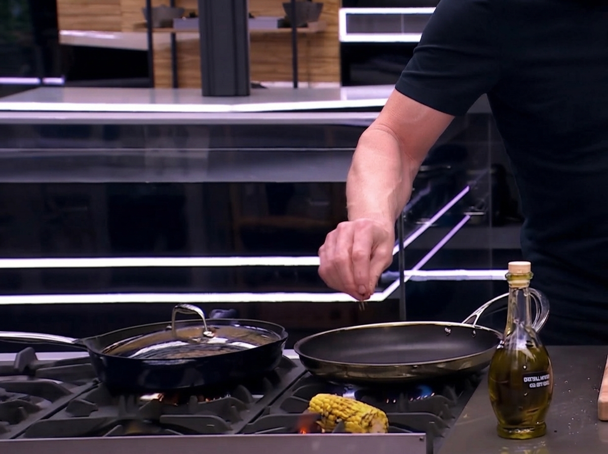 Un épi de maïs assaisonné en train dêtre rôti et grillé directement sur une flamme de gaz ouverte de la cuisinière.