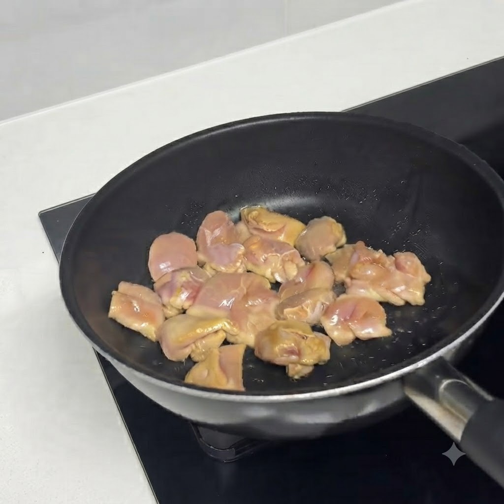 Morceaux de poulet mariné grésillant dans une poêle chaude huilée.