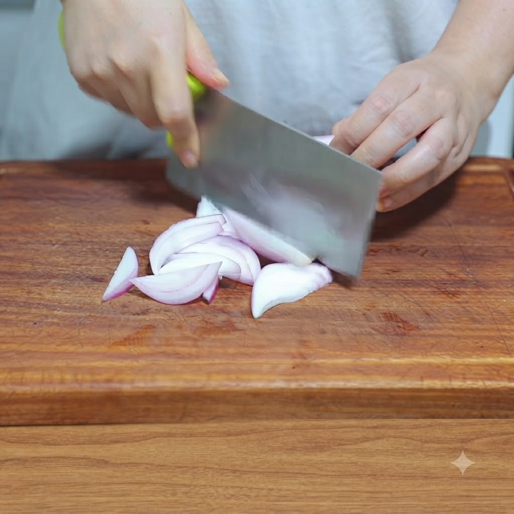 Un couteau de cuisine coupant un oignon en fines lanières sur une planche à découper en bois.