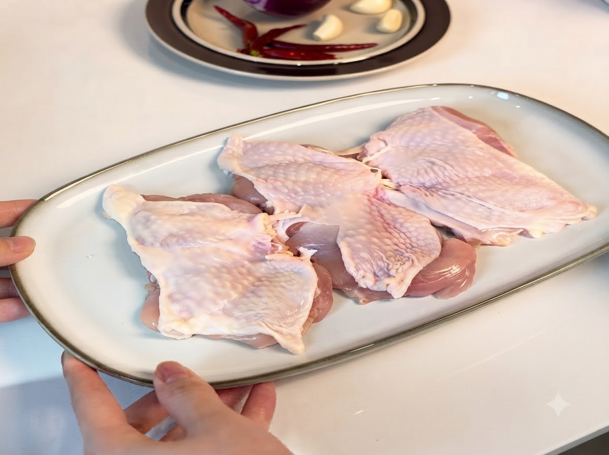 Cuisses de poulet désossées disposées sur une assiette blanche, enrobées dassaisonnements.