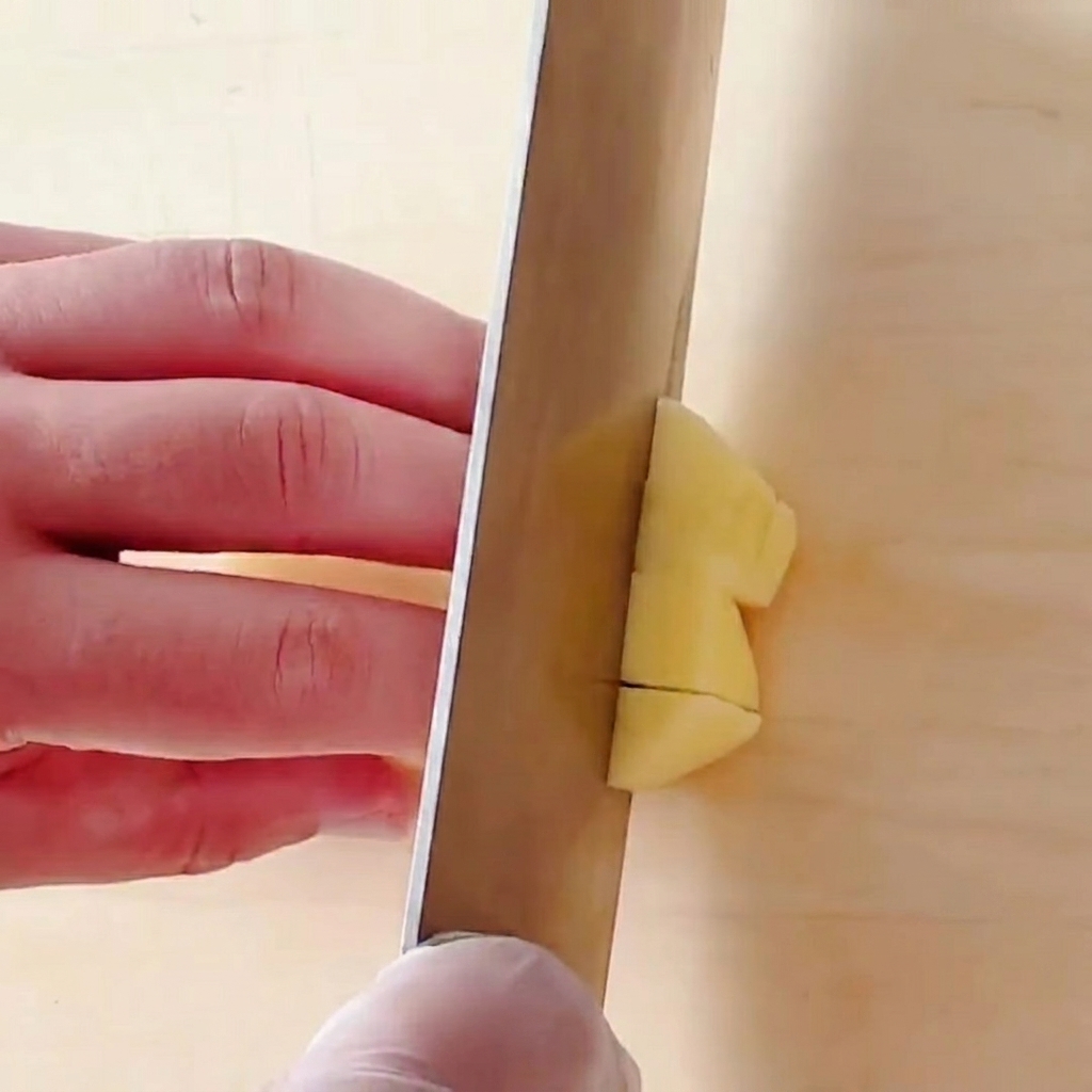 Pommes de terre coupées en petits dés réguliers sur une planche à découper en bois.