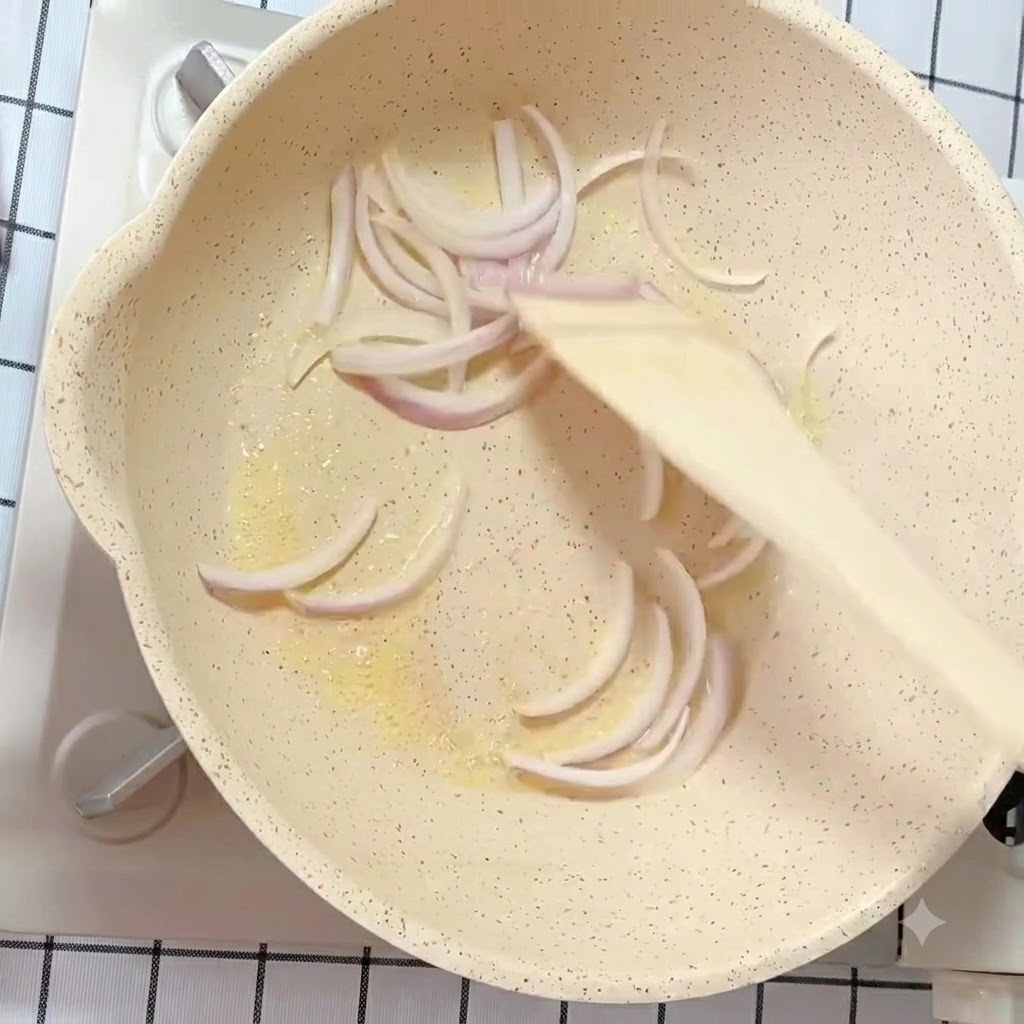 Lamelles doignons blancs et violets sautées dans une poêle beurrée avec une spatule en bois.