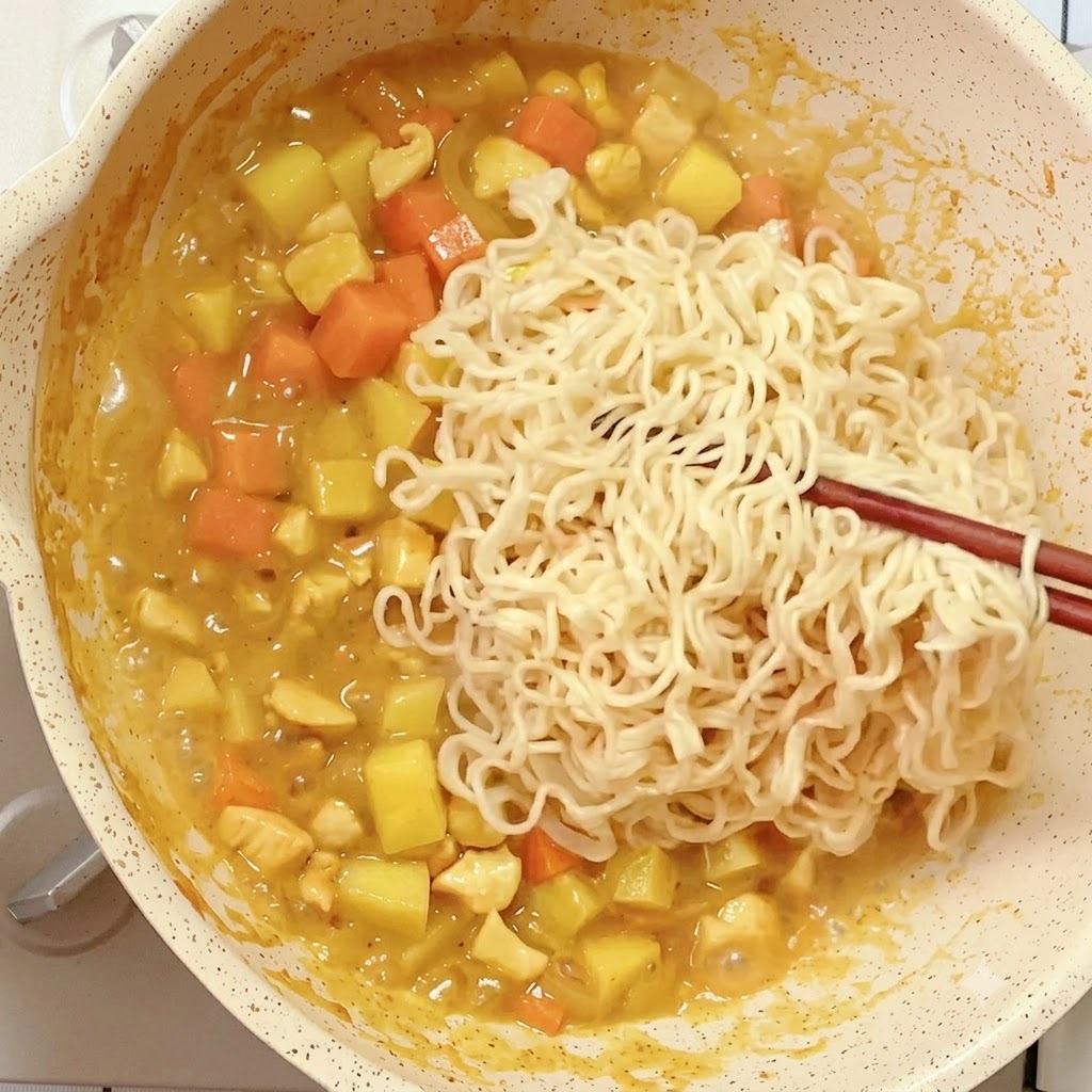 Nouilles instantanées précuites disposées avec des baguettes dans la poêle de curry en réduction.