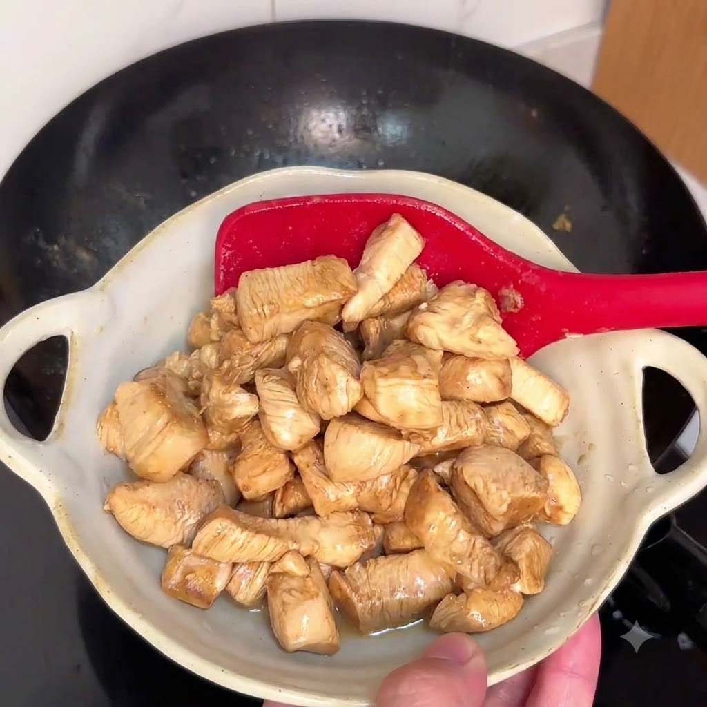 Morceaux de poulet sautant dans un wok chaud avec une spatule rouge.