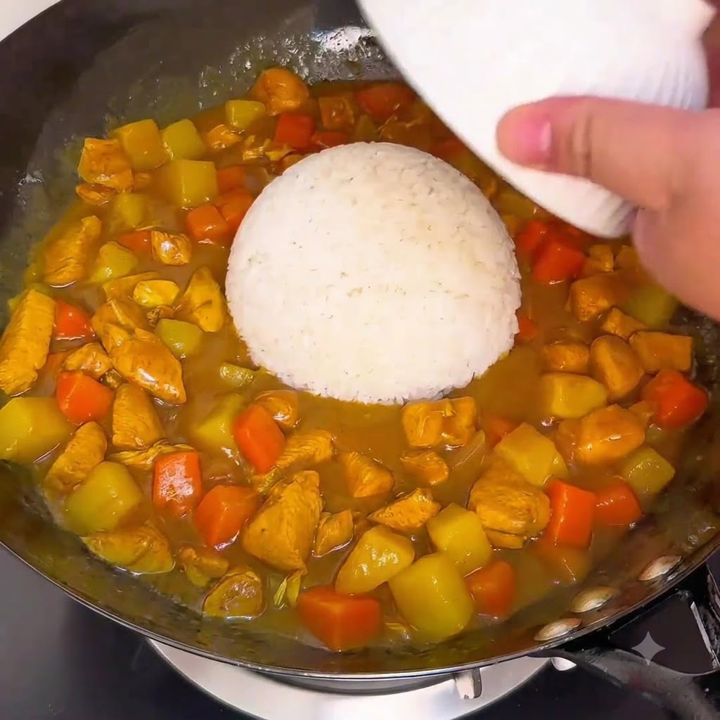 Un bol de riz blanc retourné directement dans la sauce au curry frémissante dun wok.