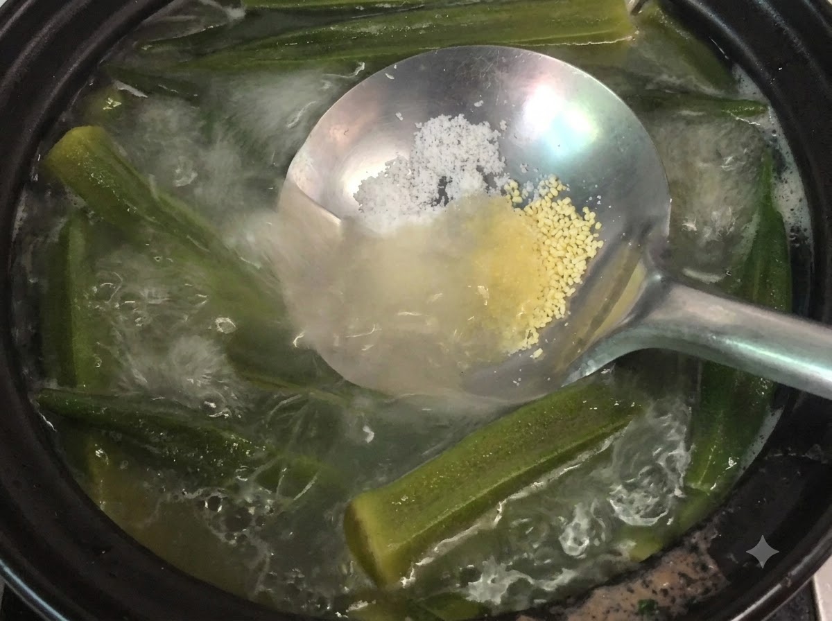 Une louche tenant du sel et de la poudre de poulet au-dessus dune casserole frémissante de soupe de gombos et dos.