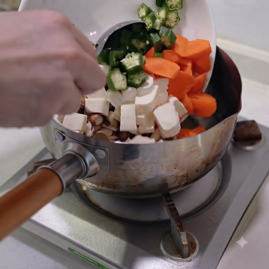 Légumes coupés et tofu versés dune assiette blanche dans une casserole en acier inoxydable.