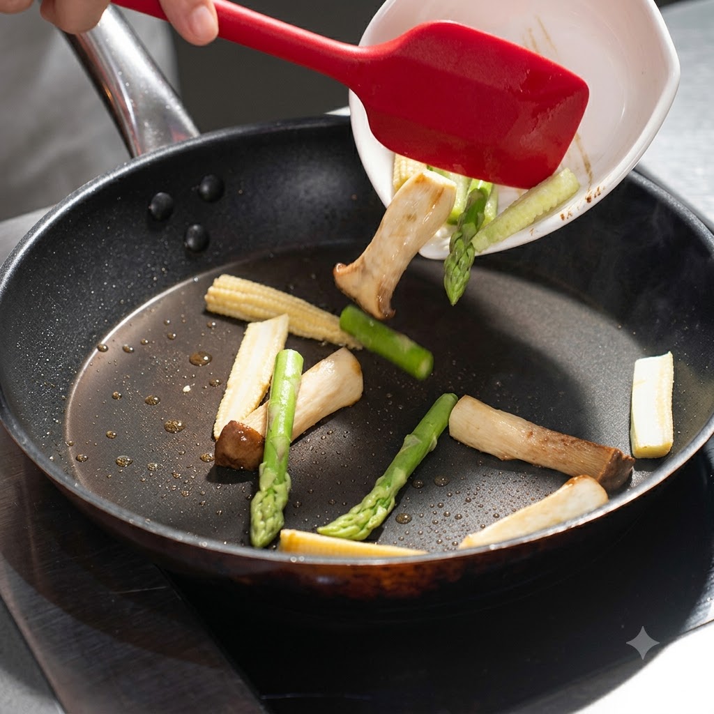 Des asperges et du mini maïs versés dun plat blanc dans la poêle avec les champignons.