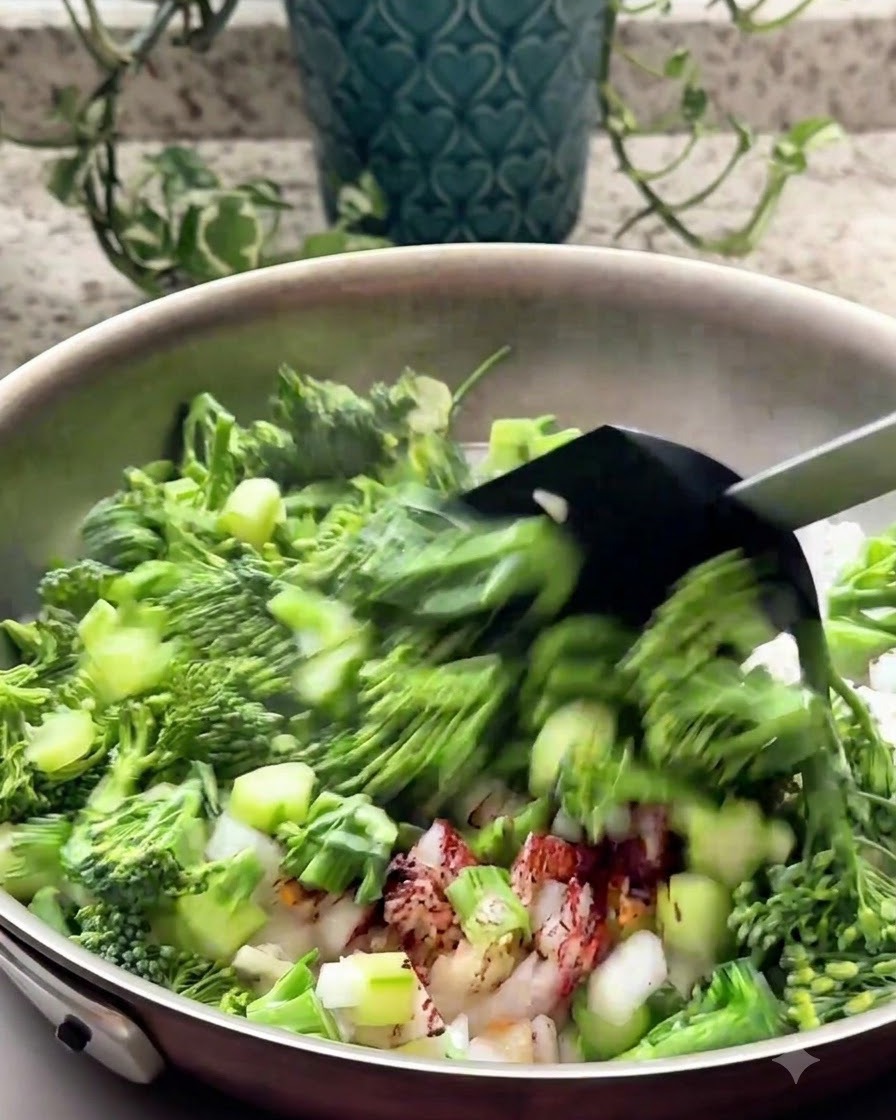 Du brocoli haché et des aromates sautant dans une poêle à laide dune spatule noire.