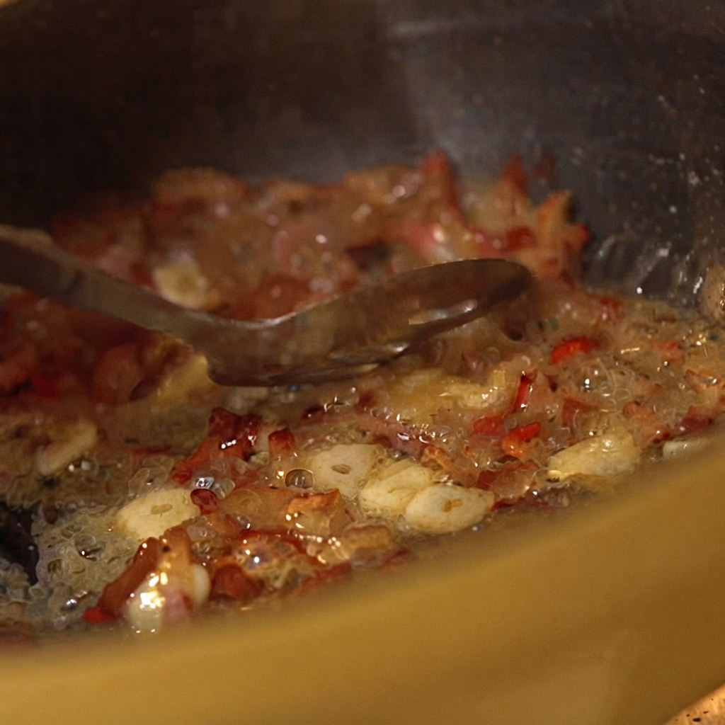 Des tomates concassées en boîte mélangées aux ingrédients de la poêle avec une cuillère.